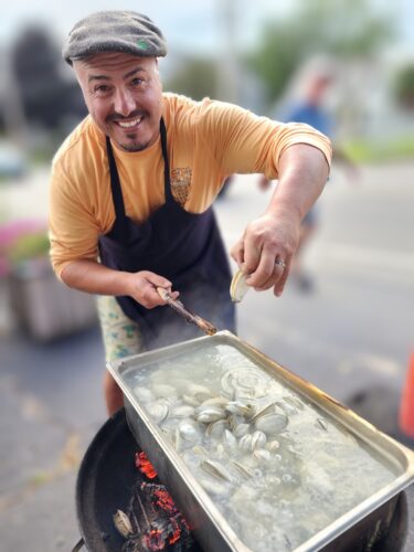 a man cooking clams on a grill